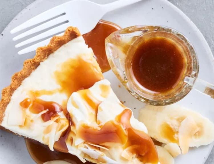 A white plate topped with a piece of pie and sliced bananas