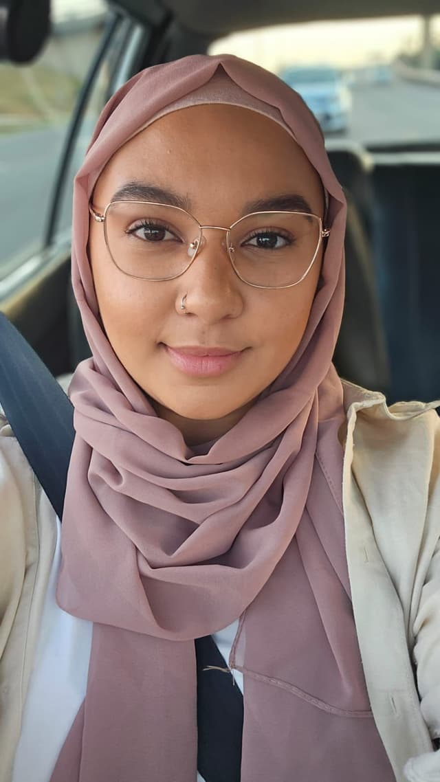 A woman wearing a headscarf and glasses in a car