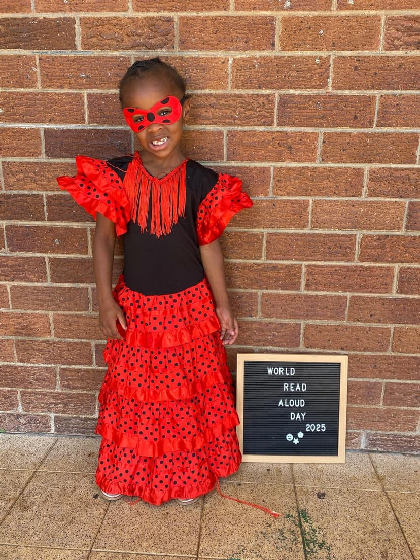 A little girl in a red and black dress and a sign