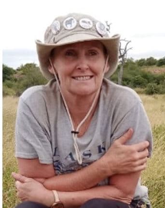A woman sitting in a field wearing a hat