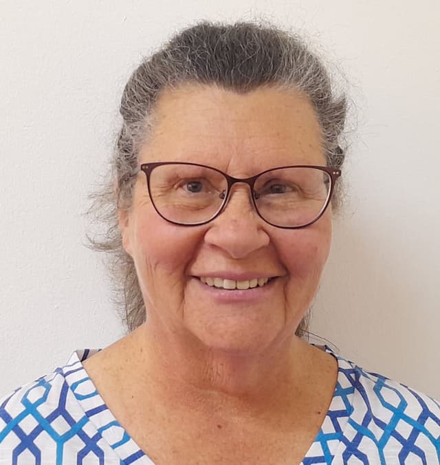 An older woman with glasses smiling for the camera